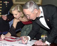 Miss America 2002, Katie Harman signs a USO poster, while performing her community service work
