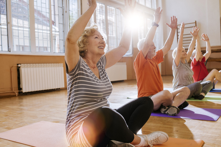 A group of active seniors enjoying a midday yoga class.