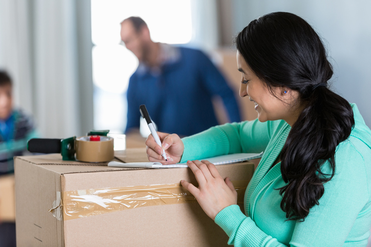 woman labeling boxes and checking inventory on moving day